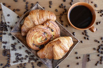 Sweet breakfast: black coffee, croissants and a roll with raisins