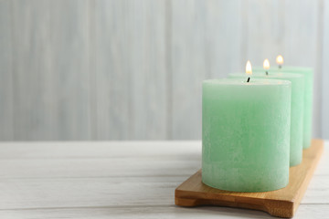 Bamboo plate with three burning candles on table, space for text