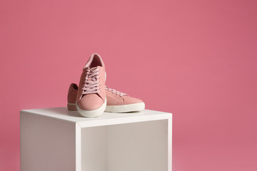 Beautiful bright stylish shoes on decorative stand against color background. Space for text