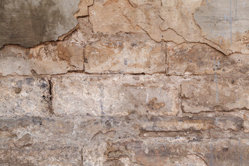 Old ruined wall facade with fallen cement and bricks. Texture background flake off plaster from house wall