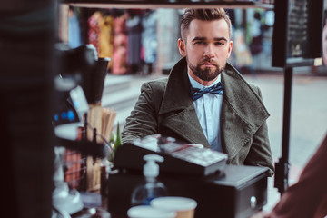 Attractive elegant man is enjoying his coffee while sitting outside at coffeeshop. 