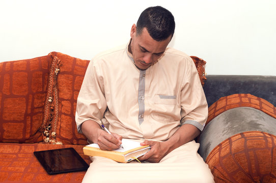 muslim businessman sitting on a morocco sofa and writing on a notebook