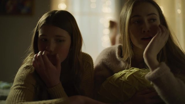 Girls laying on bed at night seeing shocking social media on cell phone / Cedar Hills, Utah, United States