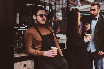 Fototapeta na wymiar Attractive happy barista in sunglasses took a coffeebreak at his own coffeeshop.