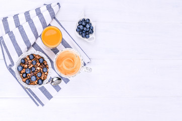 Traditional european breakfast on white wooden background. Muesli with berries, coffee and orange juice. Flat lay. Copy space.