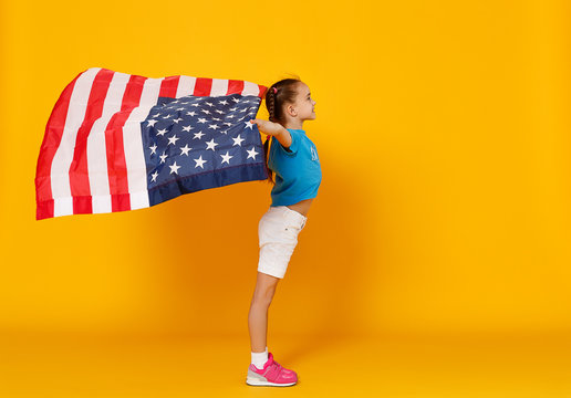 happy child girl with flag of   United States of America USA on yellow   background