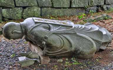 Dropped down, fallen buddhist monk granite stone statuesque in a Temple in Japan. Higo Honmyo...