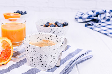 Traditional european breakfast on white wooden background. Muesli with berries, coffee and orange juice.