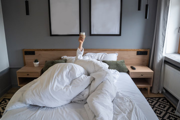Hand holding a cup of coffee at home in bed