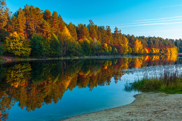 Silence at the forest lake at sunset, with reflection of sky and forest on a water smooth surface, Russia, Mari El