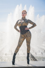 sexy curvy blonde woman with short hair wearing latex rubber catsuit and tight fetish corset....