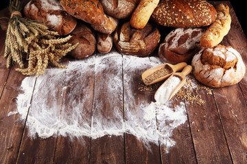 Different kinds of bread and bread rolls on board from above. Kitchen or bakery