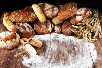 Different kinds of bread and bread rolls on board from above. Kitchen or bakery