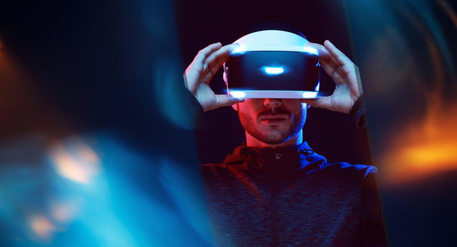 Model young man with beard in glasses of virtual reality. Augmented reality,  future technology concept. VR. Neon light.