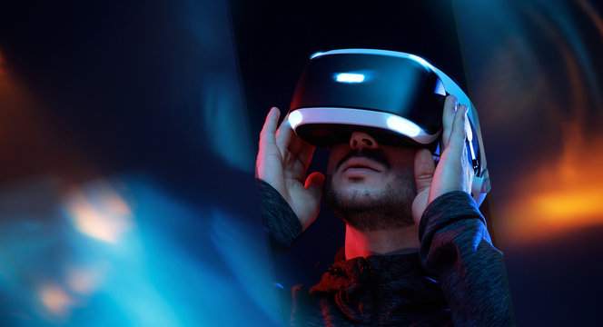 Model young man with beard in glasses of virtual reality. Augmented reality,  future technology concept. VR. Neon light.