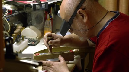 jeweler in the workshop engraves a silver spoon with beautiful painted patterns