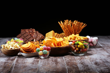 Salty snacks. Pretzels, chips, crackers in wooden bowls on table
