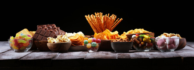 Salty snacks. Pretzels, chips, crackers in wooden bowls on table