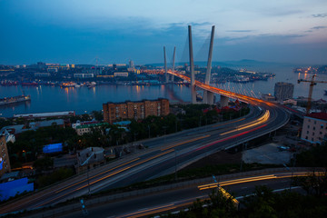 Fototapeta na wymiar Golden cable-stayed bridge road car traffic from above. Modern Vladivostok Russia night illumination. Old and modern central buildings.