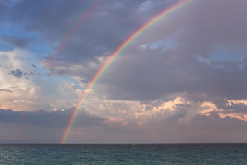 Double rainbow over the sea after the rain. Beautiful summer scenery.