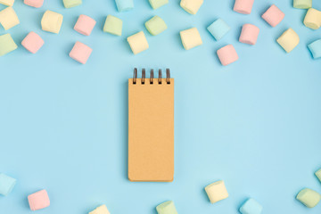 Blue paper background with marshmallow and notepad. Place for your text. Cozy sweet background