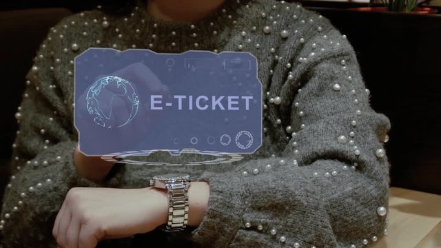 Unrecognizable woman working with HUD hologram of a smart watch with text E-ticket. Female hands with future holographic technology in wrist watches