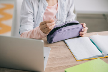 cropped view of child getting ruler out of pencil case while doing homework