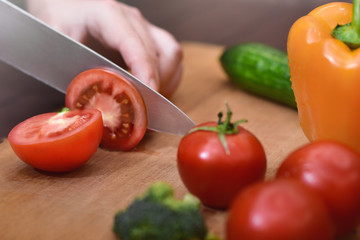 Man slicing a tomato , Bell peppers, and cucumbers .Organic ingredients for healthy eating.