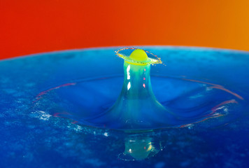 Yellow drop falling into blue water, causing amazing unique ripples. 