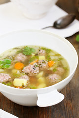 soup with meatballs in a white bowl. light soup with pork meatballs.