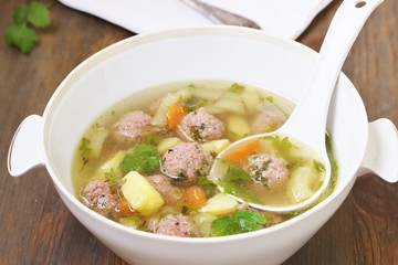 soup with meatballs in a white bowl. light soup with pork meatballs.