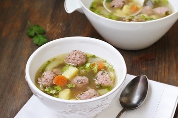 soup with meatballs in a white bowl. light soup with pork meatballs.