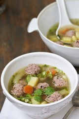 soup with meatballs in a white bowl. light soup with pork meatballs.