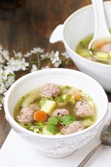 soup with meatballs in a white bowl. light soup with pork meatballs.