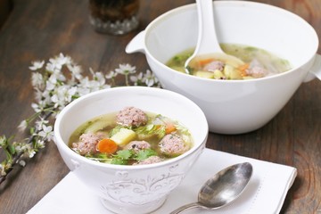 soup with meatballs in a white bowl. light soup with pork meatballs.