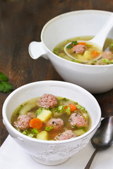 soup with meatballs in a white bowl. light soup with pork meatballs.