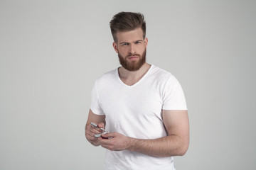 Successful man with lush ginger beard. holds the razor in his arms and looks brutally into the camera. dressed in casual clothes. stand in front of the white background