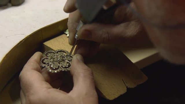 jeweler in the workshop fixes diamonds in brooches
