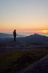 Obraz premium Silhouette of a woman contemplating the sunset from Mount Galiñeiro in Vigo, Galicia, Spain