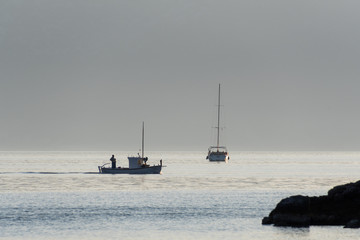A sailing boat and a fishing boat on the sea
