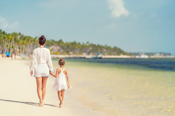 Young mother and little daughter walking on the beach in Dominican Republic