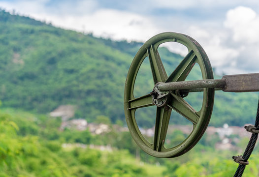 Green Pulley Wheel on the Shaft with Blur Mountain and Sky in Background.