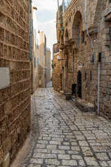 An old city narrow alley with stone walls and stone pavers
