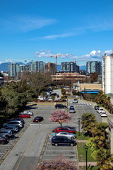 Obraz premium New construction of high-rise buildings in Richmond city, industrial construction site, construction equipment, several construction cranes on the background of mountain range and a blue cloudy sky. 