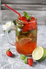 Fototapeta na wymiar Mojito lemonade with strawberries on a dark background in a trendy mug pot.