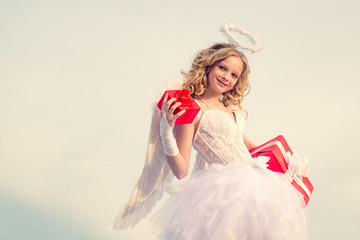 Teenager Cupid angel with gift. Cute teen Cupid angel with gift on the cloud - sky background....