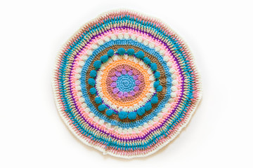 Round mandala crocheted from colored yarn. White background.