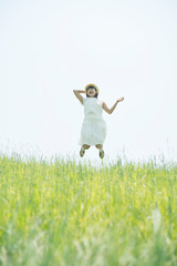 Naklejka na ściany i meble 草原でジャンプをする女性
