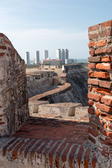 Walls of the castle of the time of the Spanish colony in Cartagena, with view of modern buildings in the background. Colombia