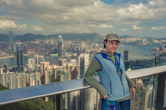 cheerful girl posing on Victoria's peak in Hong Kong, young girl is standing in front of Hong Kong view